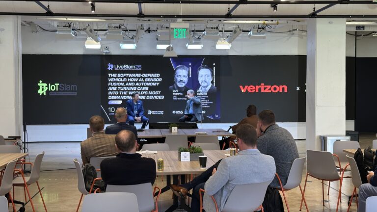 Two speakers discuss software-defined vehicles in front of the event screen.
